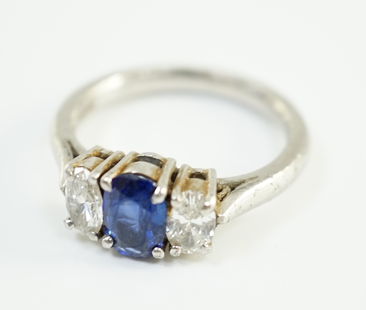 A modern platinum, singe stone oval cut sapphire and two stone oval cut diamond set ring